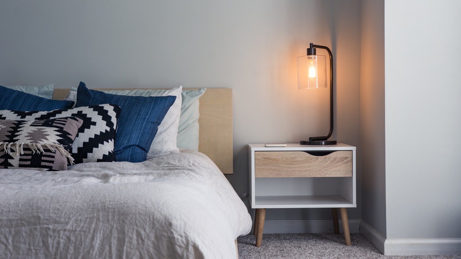 A serene Japandi room with low natural-wood furniture, soft neutral textiles, and a single ceramic vase