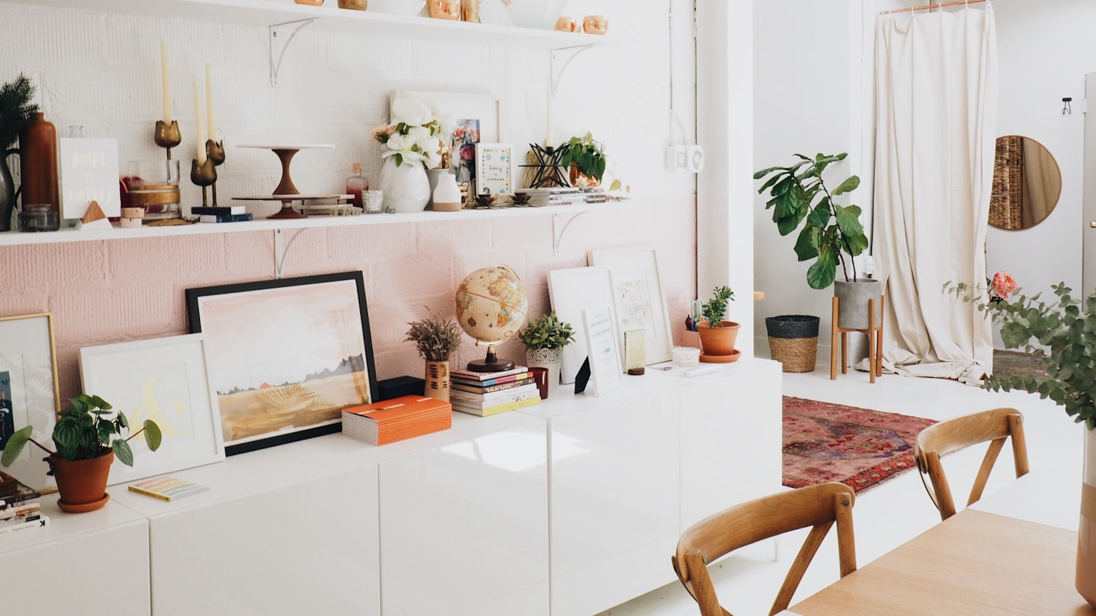A clever nook under a staircase fitted with shelves, a small seat, and a soft cushion in a bright home