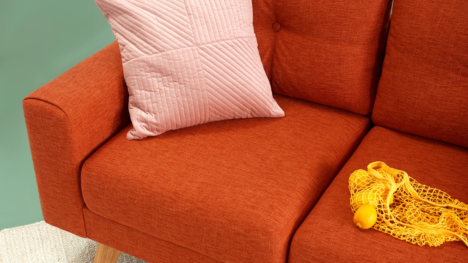 A bright, comfortable living room with a sofa, layered cushions, a coffee table, and a soft area rug